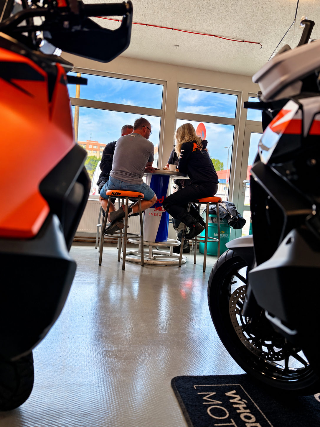 Návštěvníci hovoří v prodejně mezi motocykly