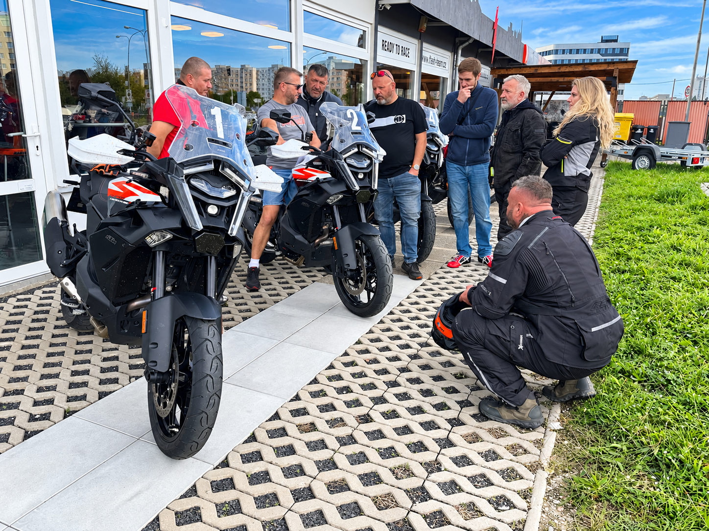Návštěvníci si prohlížejí testovací motocykly před prodejnou
