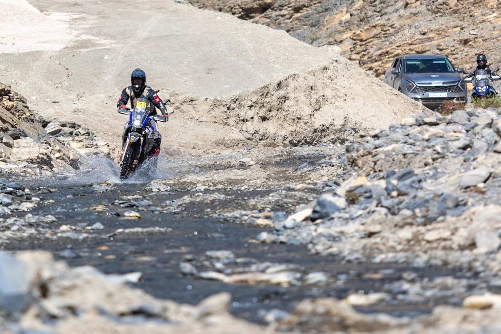 Motocyklista projíždí kamenitým korytem řeky
